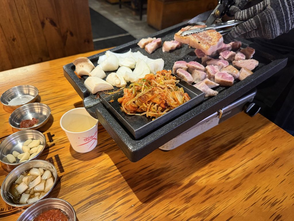 店員さんがトングとハサミで豚肉を焼いてくれている様子