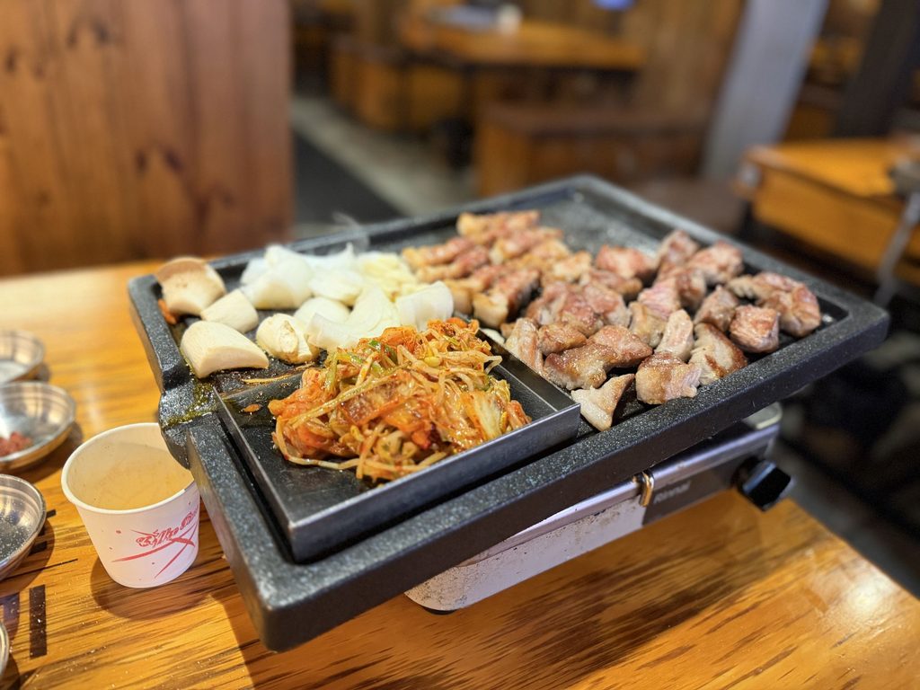 焼き上がった豚肉と、玉ねぎ・エリンギ・キムチが並ぶ鉄板